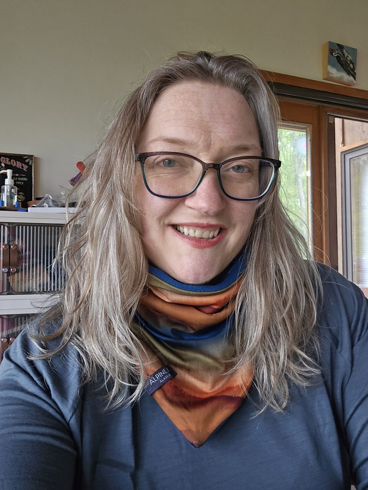 Judy Lipinski smiling, wearing glasses and a colorful scarf